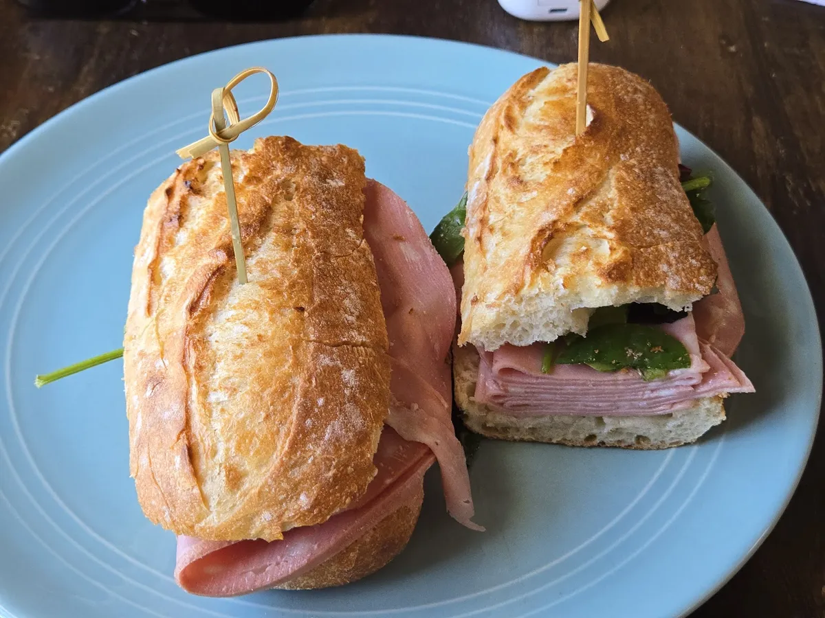 Two ham and cheese baguette sandwiches on a blue plate